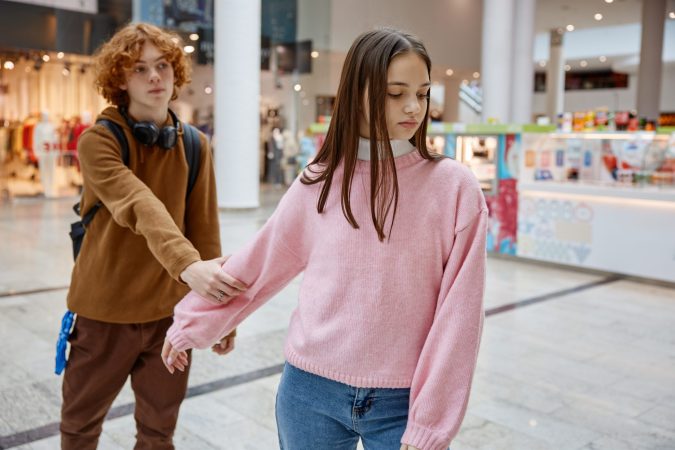 Teenage couple having quarrel during date in shopping center. Misunderstanding between young people